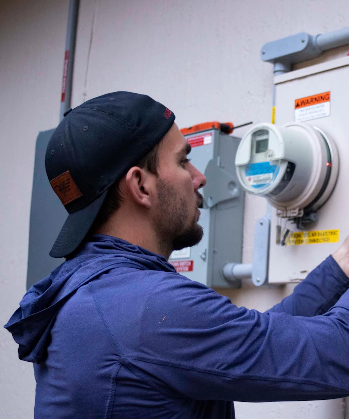 Technician working on an electrical meter outside a house